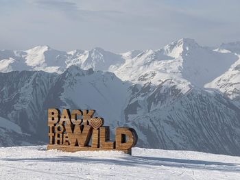 Information sign on snow covered mountains against sky