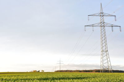 Electricity pylon on field against sky