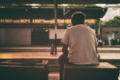 Rear view of man sitting on seat at bangkok railway station