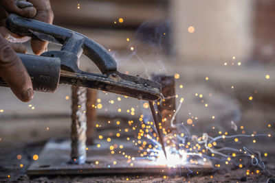 Cropped hands of worker welding metal in workshop