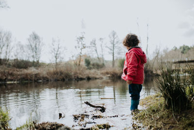 Side view of boy standing in lake against sky