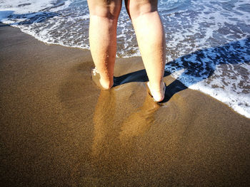 Low section of woman standing at beach