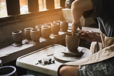 Midsection of craftsperson making pot at workshop