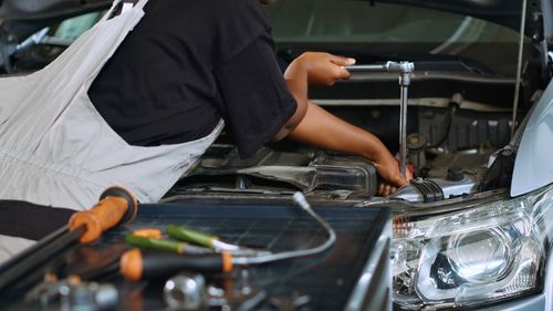 Midsection of mechanic repairing car