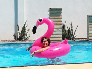 Woman with pink umbrella in swimming pool