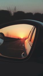 Close-up of side-view mirror during sunset