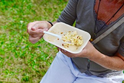 Midsection of man holding ice cream on field