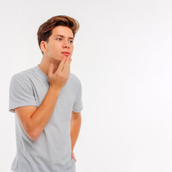 Portrait of young man looking away against white background