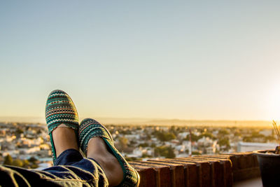 Low section of woman relaxing against clear sky