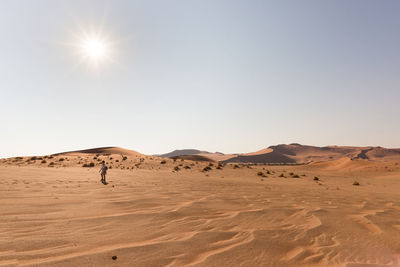 Mid distant view of woman standing on desert against sky