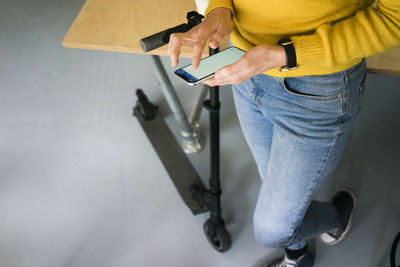 Young woman with e-scooter, using smartphone, close up