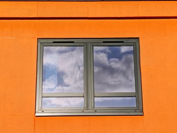 Low angle view of glass window against orange sky