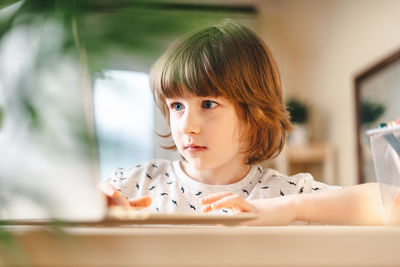 Distance learning online education. kid boy studying at home with laptop and doing school homework.