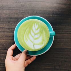 Close-up of hand holding coffee cup on table