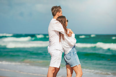 Side view of young woman standing at beach