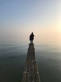 Man standing on pier at sea against clear sky
