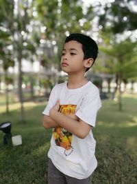 Boy standing with arms crossed in park