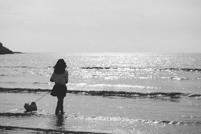 Rear view of woman with dog walking on beach