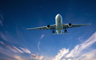 Low angle view of airplane flying against blue sky