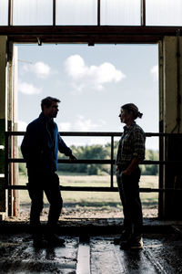 Farmers standing by door and discussing at cattle farm