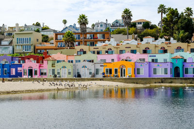 Houses by river against sky in city