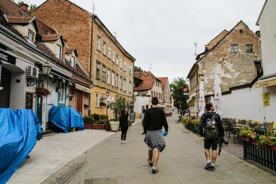 People walking on footpath amidst buildings in city