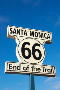 Low angle view of road sign against clear blue sky