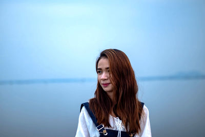 Close-up of smiling young woman against sky