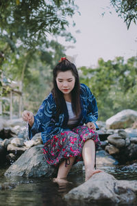 Full length of woman sitting on rock