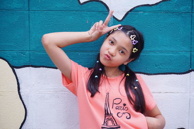 Portrait of young woman standing against wall