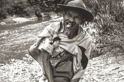 Portrait of senior man sticking out tongue while standing in forest