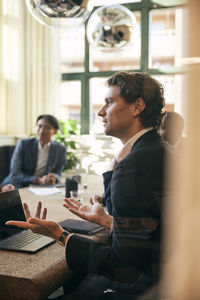 Side view of man using laptop while sitting on table