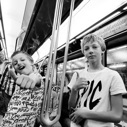 Portrait of male friends gesturing thumbs up in subway train