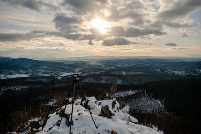 Snow covered land and mountains against sky during sunset