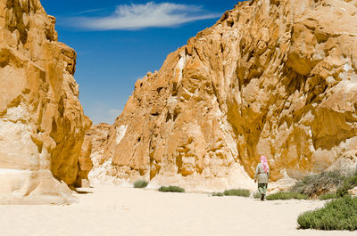 Woman standing on rock formation against sky