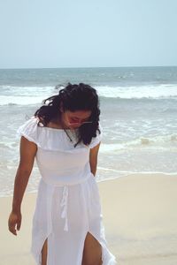 Woman standing at beach against sky