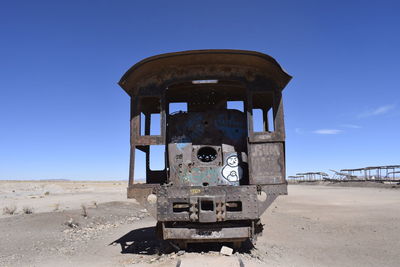 Abandoned vehicle on land against clear blue sky