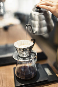 Cropped image of barista pouring boiling water in coffee filter at counter