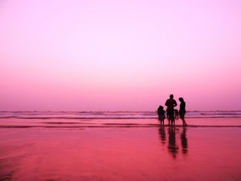 Silhouette people on beach against sky during sunset