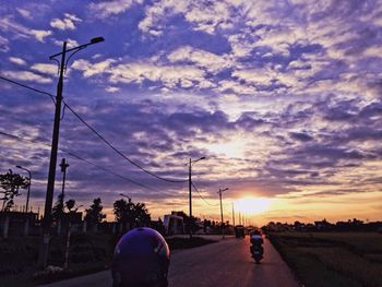 Rear view of silhouette woman walking on road against sunset sky