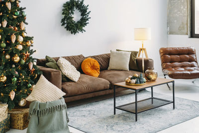 Christmas background of livingroom, background. baubles and wreath by sofa in golden and green color