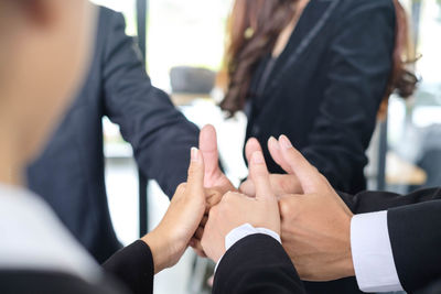 Cropped image of business people gesturing thumbs up at office