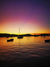 Sailboats in sea against clear sky during sunset