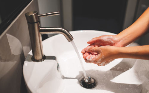 Woman washing hands in sink at home