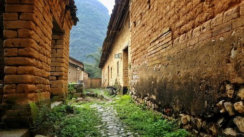 Alley amidst old houses by mountain against sky