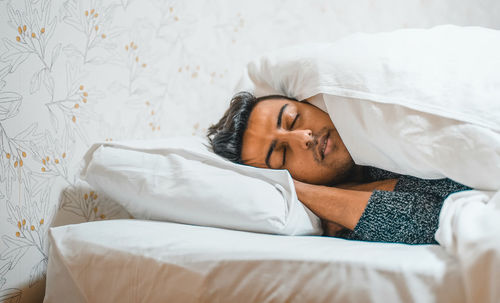 Young man sleeping on bed