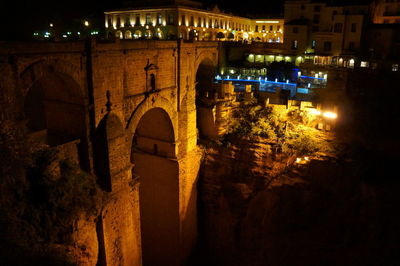 Illuminated bridge over street in city at night