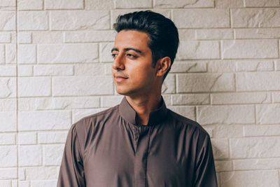 Portrait of young man looking away against wall