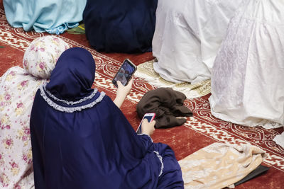 A high angle view of a woman sitting on a prayer mat