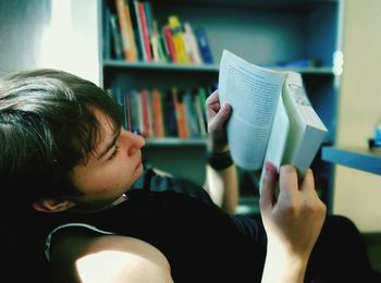 Midsection of boy holding book at home
